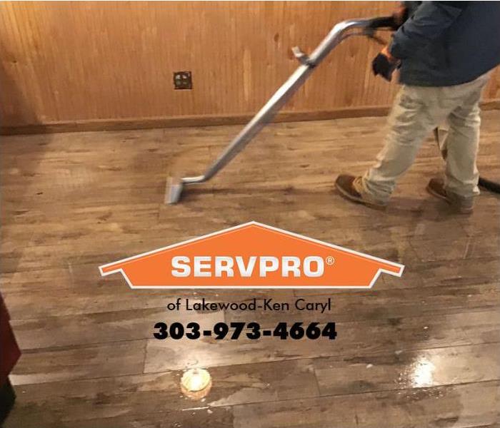 A SERVPRO technician is shown extracting storm water from a floor.