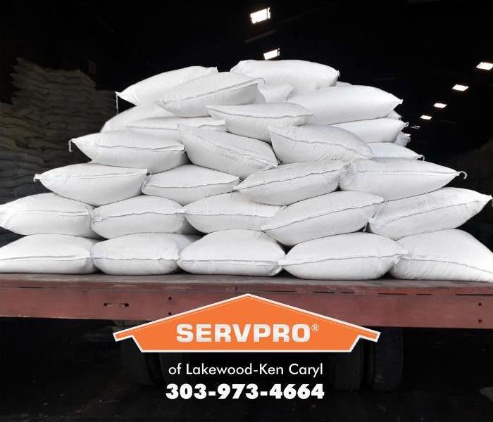 Large white industrial-sized fertilizer bags sit on a trailer inside a warehouse.